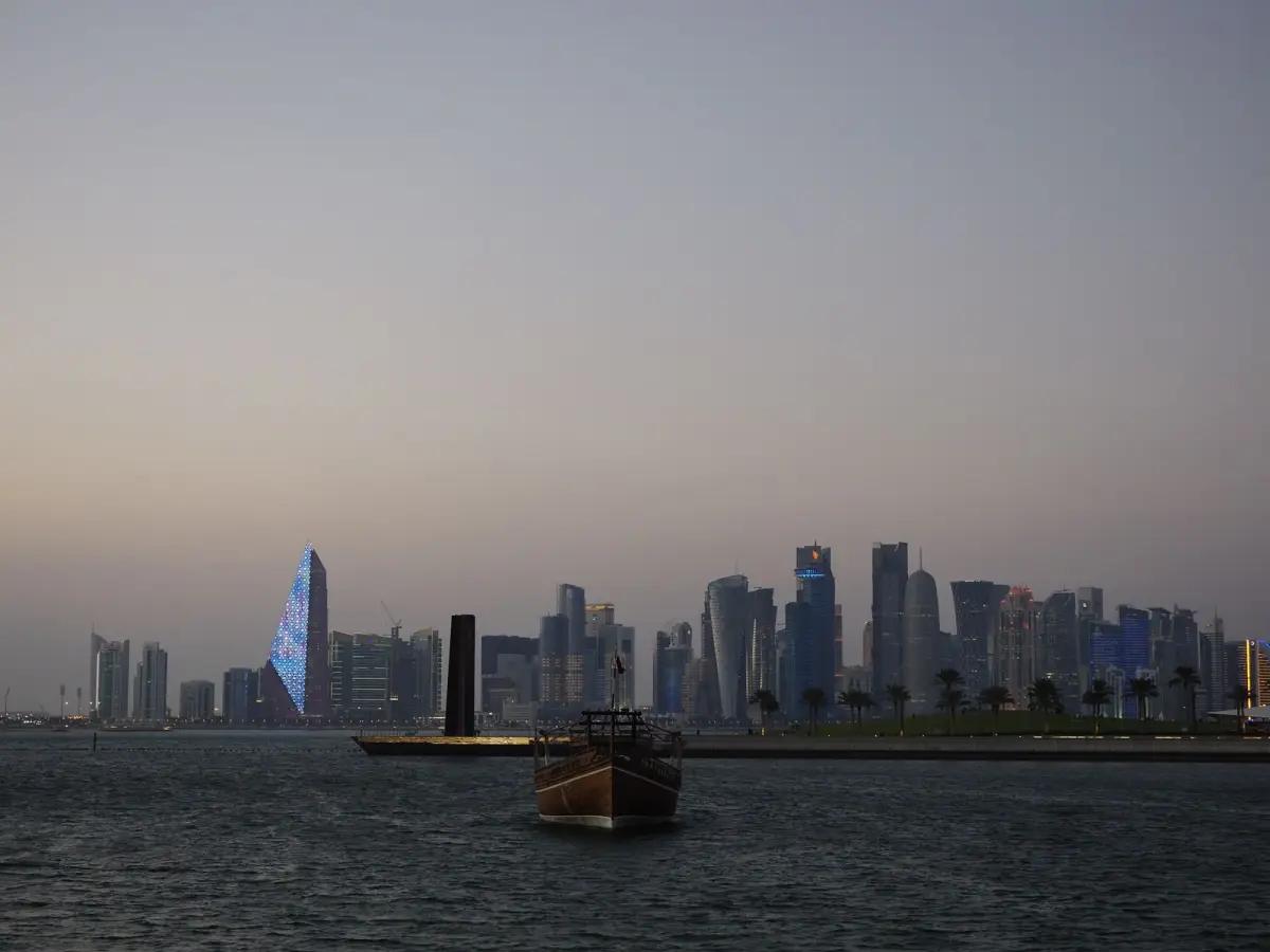 Qatar Airways reward flights via Doha — Doha skyline and traditional dhow boat at dusk